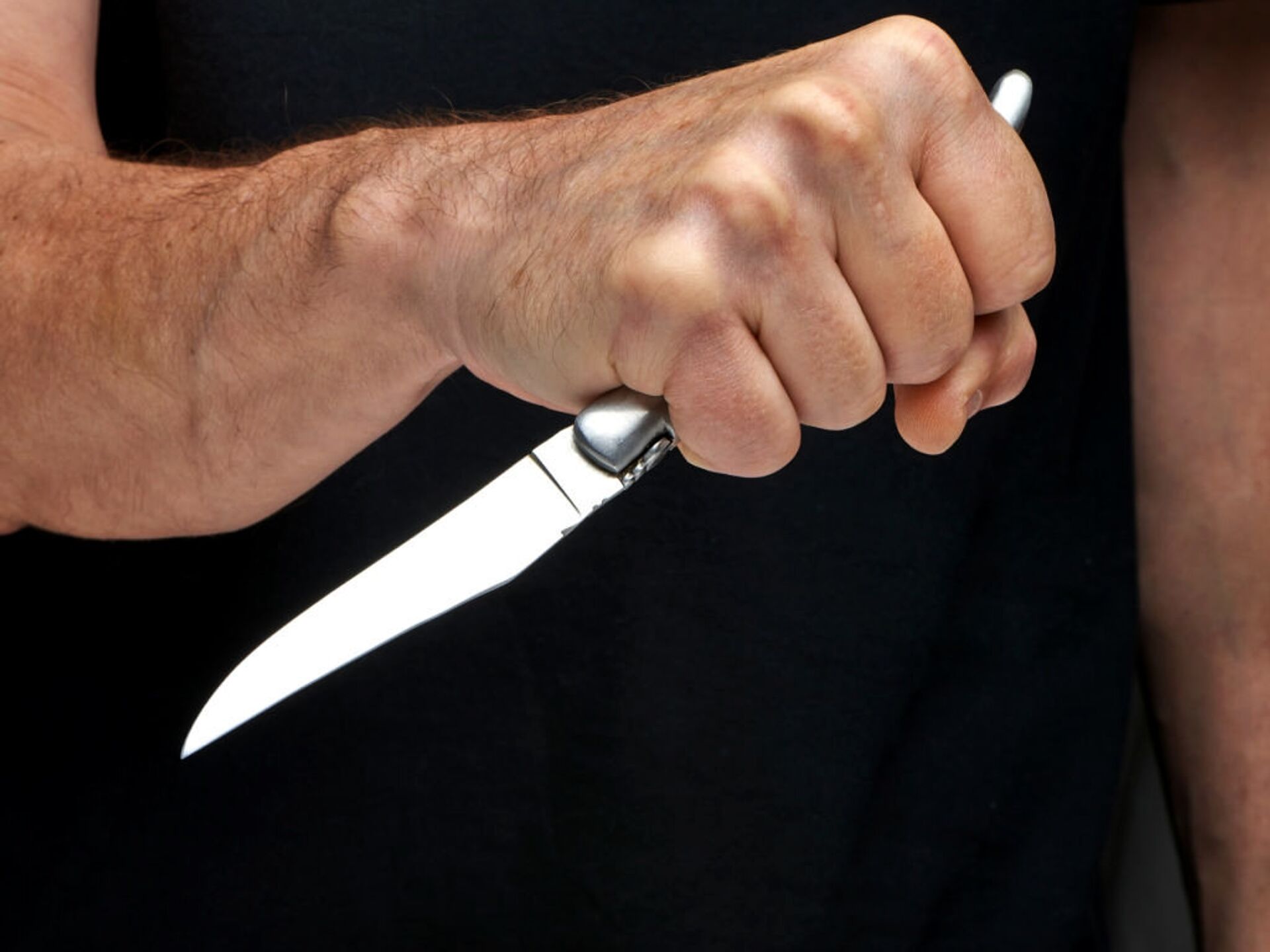 Нанесение ножевых. Кухонный нож в мужской руке за спиной.